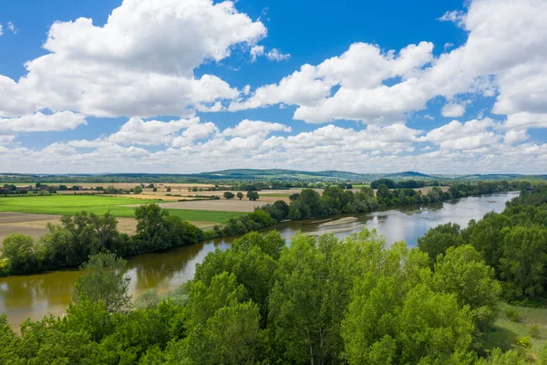 Geniş yeşil alanlar ve sık ağaçlar kıvrımlı Loire nehrini çevreleyen tepeler ve dramatik kümülüs bulutlarıyla doldurur parlak yaz gökyüzünü..