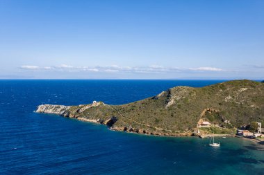 Kapsamlı bir hava perspektifi, Yunanistan 'ın Porto Kagio kentinde, temiz bir gökyüzünün altında kıyıya demir atmış tek bir yelkenliyle engebeli bir yeşil yarımadayı derin mavi sulara daldırıyor. Sahne canlı ve canlı, doğal dokuları vurguluyor ve açık