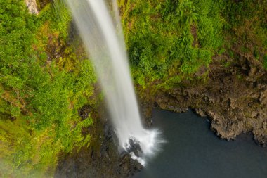 Tad Yuang şelalesinin güçlü akıntısını, güney Laos 'taki Bolaven Platosu' ndaki yoğun yeşil yapraklarla çevrili engebeli bazalt kayalarının üzerine düşen koyu yeşil bir havuza havadan yakalar. Resim zıt dokuları vurgular