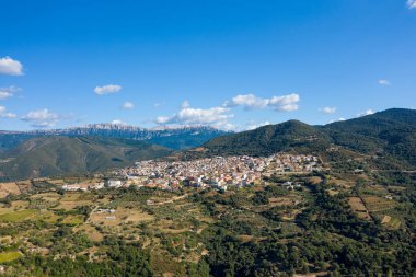 Orgosolo köyünün hava perspektifi zeytin korulukları, yama alanları ve Sardunya 'da dağınık bulutlarla kaplı açık mavi gökyüzünün altındaki dramatik dağ sırtlarıyla çevrili..