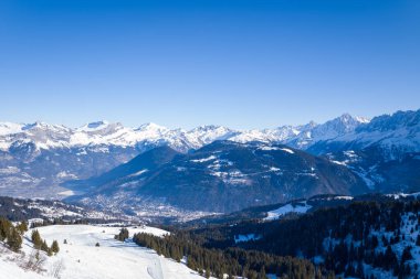 Passy 'nin üstündeki Fransız Alpleri' nin karla örtülü tepeleri, koyu yeşil ormanları ve açık mavi gökyüzünün altındaki engebeli tepeleri. Parlak kış güneşi keskin zıtlıklar ve sakin bir dağ atmosferi yaratır..