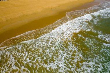 Yumuşak dalgalar, İtalya 'nın geniş altın kumsal sahili üzerinde köpüklü desenler oluşturur. Hava manzarası Adriyatik kıyılarının doğal dokularını ve ince renk eğimlerini gün ışığı altında vurguluyor.