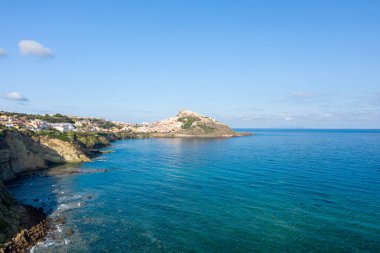 Castelsardo köyünün panoramik manzarası Akdeniz 'in berrak turkuaz sularının üzerinde, dağınık mavi bulutların altında, kayalık bir çıkıntıya tünemişti..