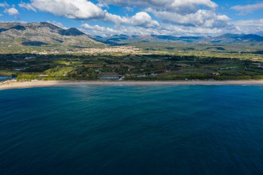 Uçsuz bucaksız bir hava perspektifi derin mavi denizi, bereketli kırsal bölgeleriyle ve engebeli dağlarıyla Sardunya 'nın Orosei yakınlarındaki dramatik bulutların altında uzun kumlu bir plajla buluşurken yakalıyor..