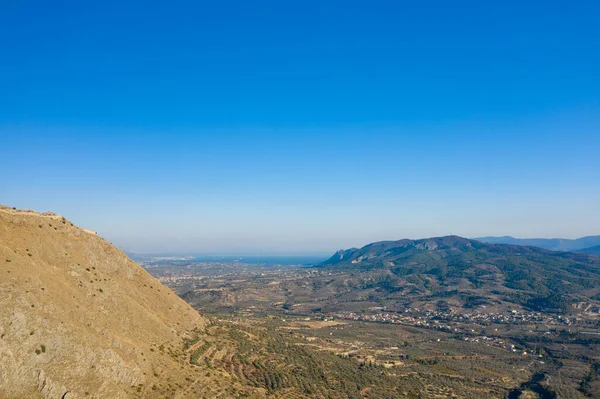 Akrokorinth 'in kayalık yama arazisi, dağınık köyler ve Yunanistan' da berrak, canlı bir gökyüzünün altındaki uzak mavi denizden geniş bir bakış açısı.