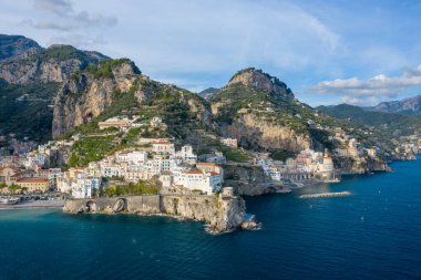 İtalya 'nın Amalfi kentindeki sarp kayalıklardan süzülen, koyu mavi Akdeniz sularına bakan, güneşli, bembeyaz binalar. Dramatik kıyı şeridi yemyeşil tepeler ve engebeli dağlarla çevrili berrak bir gökyüzü altında..