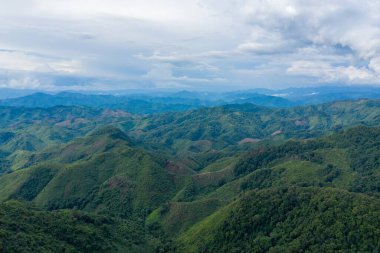 Sonsuz yeşil dağ sırtları Laos 'un Phonsavan ve Phou Khoun arasındaki kırsal bölgede dramatik bir gökyüzünün altında uzanıyor. Manzara bereketli bitki örtüsü, dalgalı tepeler ve uçsuz bucaksız bir doğal alan hissi barındırır..