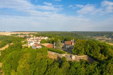 Tarihi taş şatosu, kilise kulesi, kırmızı kiremitli çatıları, sık yeşil ormanlık ve açık arazilerle çevrili Hattonchatel köyünün yükseltilmiş yaz manzarası. Sahne ortaçağ mimarisi ve sakin kırsal manzarayı vurguluyor