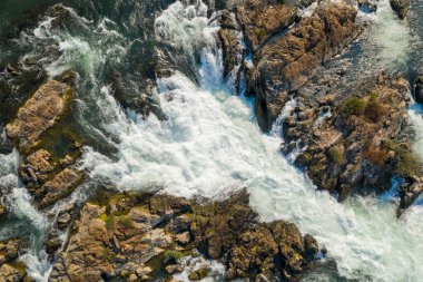 Laos 'un güneyindeki Champasak Eyaleti' ndeki Li Phi Şelalesi olarak da bilinen Tat Somphamit Şelaleleri 'nde engebeli taşların arasından akan girdap gibi beyaz suyun ayrıntılı hava görüntüsü. Sahne kayaları, enerjik nehir akışını ve inceliği vurguluyor.