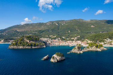 Yunanistan 'ın Epirus kentinde yer alan Parga' nın yüksek açılı manzarasında tarihi bir tepe kalesi, çam ağaçlarıyla kaplı adalar ve İyon Denizi boyunca renkli rıhtım evleri yer alıyor. Akdeniz manzarası yeşil tepeler ve berrak bir suyun altındaki derin mavi sularla çerçevelenmiştir.