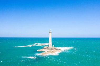 Uzun bir deniz feneri engebeli kayaların üzerinde canlı turkuaz denizle çevrili ve Cap de la Hague 'de açık mavi bir gökyüzünün altında tek başına duruyor. Sahne parlak, açık ve deniz direncini çağrıştırıyor..