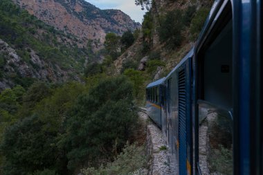 Yunanistan 'ın Kalavrita kenti yakınlarındaki Vouraikos Vadisi' nde yoğun yeşillik ve dik kayalıklarla çevrili engebeli bir dağ yolu boyunca dar çaplı bir tren esiyor. Sahne dramatik manzarayı ve bu manzaralı tren yolu boyunca eşsiz yolculuğu yakalar..