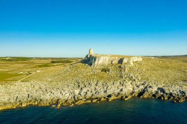 İtalya 'nın Porto Badisko kentindeki Adriyatik Denizi' ne bakan engebeli kireçtaşı uçurumlarının tepesinde tek bir taş gözetleme kulesi bulunuyor. Manzara kayalık arazi, açık kırsal alan ve açık mavi gökyüzüne sahiptir..