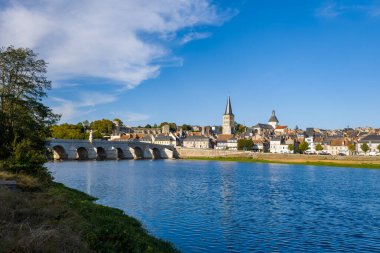 Açık sabah güneşi tarihi taş köprüyü ve La Charite sur Loire 'ın geleneksel çatılarını aydınlatırken, nehir kenti üzerinde kilise kulesi yükseliyor. Sakin mavi su ve yemyeşil çerçeve sakin Loire Valley manzarası