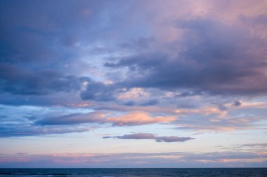 Agde yakınlarındaki sakin bir denizin üzerinde mavi ve pembe tonlarda genişleyen pastel bulutlar alacakaranlıkta sakin ve havadar bir kıyı atmosferi yaratıyor..
