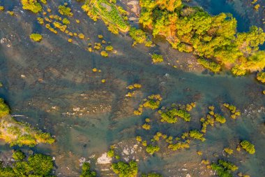 4000 Laos adasındaki Mekong Nehri 'nde dağınık yeşil adaları ve sığ kayalık kanalları görüntüler. Sıcak gün ışığı, bu sakin nehir manzarasında suyun, bitki örtüsünün ve açıkta kalan nehir yatağının doğal örneklerini vurgular.