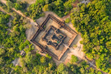 Kamboçya 'nın Angkor bölgesinde yoğun tropik ormanlarla çevrili Banteay Samre tapınağı kompleksinin simetrik tepeden tırnağa perspektifi. Eski kumtaşı yapısı kırsal açıklık ve canlı yeşillik ile çerçevelenmiş sıcak gün ışığında, vurgulanıyor