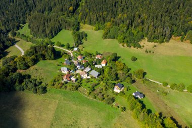 Kırmızı ve gri çatıları olan dağınık evler yeşil çayırlar ve Chartreuse Massif 'in yamaçlarında sık ormanlar arasında yuva yapar. Manzara, bu ikonik alp bölgesinin sakin atmosferini ve doğal örüntülerini yakalar..