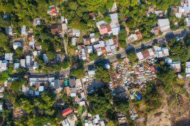 Dağılmış evleri, yemyeşil otlakları ve görünür bir mezarlığı olan küçük bir Vietnam köyünün yüksek açılı insansız hava aracı görüntüsü. Bu görüntü, Güneydoğu Asya 'daki kırsal yaşamın organik düzenini ve canlı dokusunu yansıtıyor..