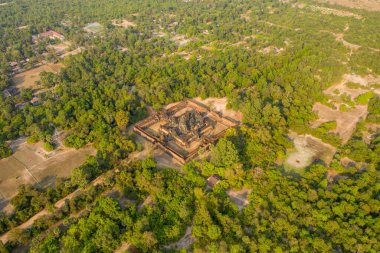 Kamboçya 'nın Angkor bölgesinde yoğun yeşillik ve kırsal açıklıklarla çevrili Banteay Samre tapınağının yüksek açılı perspektifi. Antik kumtaşı yapısı, sıcak gün ışığı altında geniş tropikal manzaranın ortasında göze çarpar..