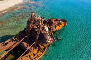 Yunanistan 'ın Gythio kenti yakınlarındaki kumlu bir kıyı şeridi yakınlarında paslanmış Dimitrios gemi enkazının hava perspektifi kısmen berrak, canlı turkuaz suya battı. Güneş ışığı paslanmış metali aydınlatır ve su altı kaya oluşumlarını ortaya çıkarır..