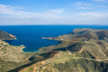Yunanistan 'ın Magne kentindeki derin mavi Akdeniz' e uzanan engebeli bir yarımadanın havadan görünüşü. Sahnede dolambaçlı yollar, dokulu tepeler ve parlak bir gökyüzü altında dağınık bitki örtüsü yer alıyor..