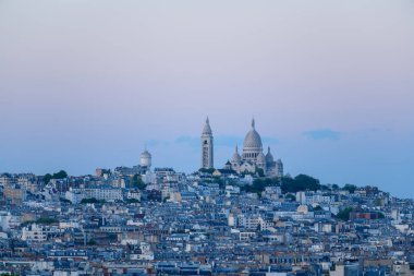 Montmartre, Paris 'in çatılarından yükselen Sacre Coeur Bazilikası' nın engin manzarası, sakin mavi ve pastel gökyüzünün altında..