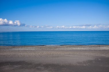 Sakin bir çakıl taşı ve sahil şeridinin minimalist görüntüsü bulutların dağıldığı berrak bir gökyüzünün altında hala mavi suyla buluşuyor. Huzurlu deniz manzarası, sakin ve açık uzayı çağrıştırır..