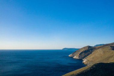 Yunanistan 'ın Cap Tenare kentindeki kayalık kayalıklarla karşılaşan derin mavi Akdeniz sularının geniş manzarası. Açık gökyüzü ve keskin kıyı şeritleri bir açıklık ve sakinlik hissi uyandırıyor..