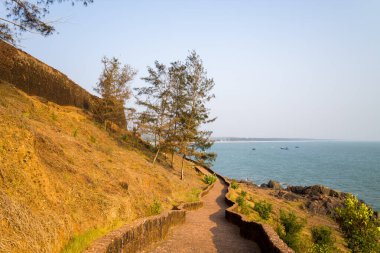 Güneşli taş yol yıpranmış kale duvarının yanında kıvrımlı ve Hindistan 'ın Bekal kentindeki kayalık kıyı şeridine doğru iner. Yumuşak okyanus manzarası ve seyrek yeşillik sakin ve açık bir hava yaratır..