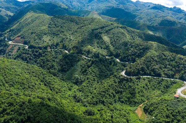 Laos 'un başkenti Phou Khoun ile Luang Prabang' ın manzaralı güzergahındaki gür, ormanlı tepeler ve vadilerden dolambaçlı bir dağ yolu örüyor. Manzara, katmanlı sırtlar, kalın bitki örtüsü ve çarpıcı güneş ışığıyla zıt gölgeler oluşturur.