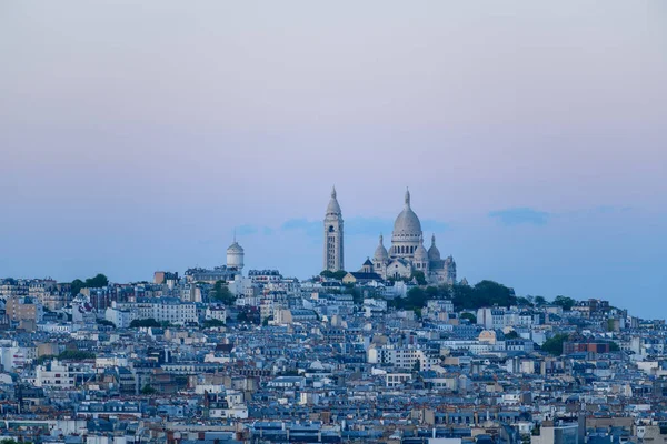 Montmartre, Paris 'in çatılarından yükselen Sacre Coeur Bazilikası' nın engin manzarası, sakin mavi ve pastel gökyüzünün altında..