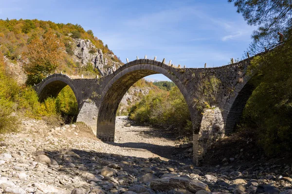 Tarihi Plakidas Köprüsü 'nde Yunanistan' ın Epirus kenti Kipoi yakınlarındaki renkli sonbahar yaprakları ve engebeli tepeler arasında kuru bir kayalık nehir yatağını kaplayan üç zarif taş kemer bulunuyor. Parlak gün ışığı desenli duvarcılığı ve doğal manzarayı gözler önüne seriyor.