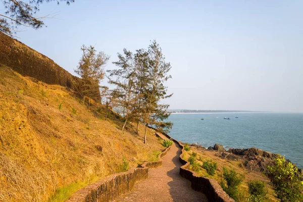 Güneşli taş yol yıpranmış kale duvarının yanında kıvrımlı ve Hindistan 'ın Bekal kentindeki kayalık kıyı şeridine doğru iner. Yumuşak okyanus manzarası ve seyrek yeşillik sakin ve açık bir hava yaratır..
