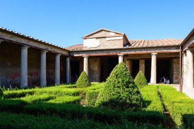 İtalya 'nın Pompei kentindeki Menander Hanedanı' ndaki sütunlu portikaların altında manikürlü çitleri ve simetrik çalı olan klasik bir Roma bahçesi bulunuyor. Parlak güneş ışığı ve açık mavi gökyüzü mimari sütunları, fayanslı çatıları ve