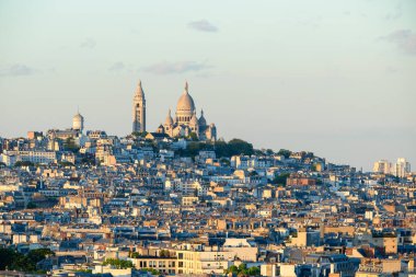 Sacre Coeur Bazilikası tarafından taçlandırılan Montmartre 'nin yükseltilmiş manzarası katmanlı çatılar ve yumuşak altın güneş ışığı sakin bir şehir manzarası yaratıyor..