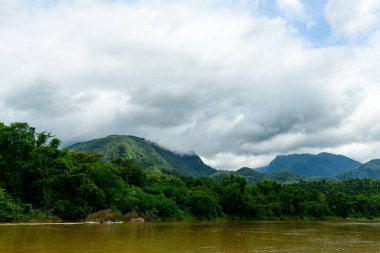 Çamurlu Nam Ou Nehri 'nin üzerinde ve kuzey Laos' taki Muang Ngoi yakınlarında yoğun yeşil tepeler üzerinde yoğun bulutlar uzanıyor. Manzara canlı ormanlar, dokulu dağ yamaçları ve sakin nehir kenarı atmosferine sahiptir..