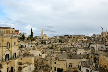 Matera, İtalya 'ya geniş bir bakış açısı, yoğun bir dizi tarihi taş bina, dokulu cepheler ve antik bir gökyüzü altında yükselen önemli katedral kulesi.