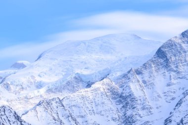 Geniş, karla kaplı yamaçlar ve engebeli tepeler Mont Blanc 'ın üst kısımlarını belirler. Yumuşak mavi gökyüzü ve hafif gün ışığı sakin bir alp havası yaratır..