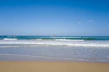 Dalgalar, Kumihamacho 'daki Shotenkyo Sahili' nin pürüzsüz kumlu sahillerinde geniş bir gökyüzü ve uzak adacıklar oluşturarak sakin bir sahil atmosferi oluşturur..