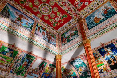 Canlı anlatılar ve süslü mandala desenleri, Laos, Vientiane 'deki Pha That Luang' daki bir Budist tapınağının kırmızı tavanını ve üst duvarlarını süslüyor. Eserde mitolojik figürler, hikaye anlatma sahneleri ve karmaşık altın ayrıntılar yer alıyor.