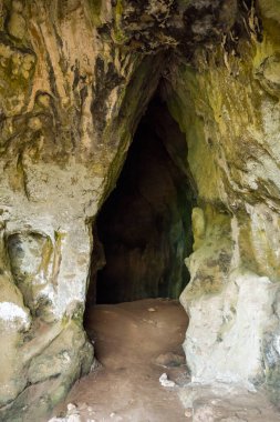 Sert, yıpranmış taş yüzeyli bir mağara girişi ve Messenia, Mora 'da davetkar bir geçiş. Doğal dokular ve sessiz tonlar entrika ve antik jeoloji hissi yaratır..