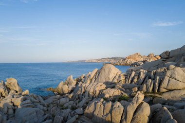 Yıpranmış granit oluşumları, Akdeniz 'in sakin mavi sularına tepeden bakar. Capo Testa, Sardunya' da, berrak bir gökyüzünün altında, yumuşak doğal ışıkla..