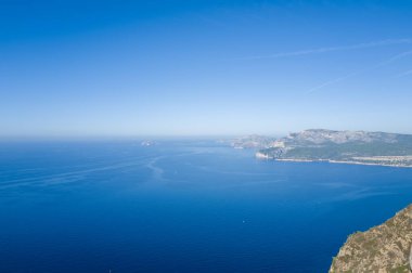 Cassis yakınlarındaki engebeli Calanques kayalıkları ve derin mavi Akdeniz 'in geniş hava perspektifi. Açık gökyüzü ve güneş ışığı canlı renkleri yükseltir ve açık, sakin atmosferi sağlar..