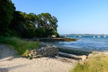 Vahşi otlarla çevrili güneşli bir kumlu yol Berder Adası 'nda sakin mavi sular ve demirlemiş teknelerle dolu gelgit kıyılarına bakan taştan bir duvara yol açar. Bereketli çam ağaçları sakin sahil boyunca gölge sağlar..