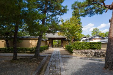 Çam ağaçları ve manikürlü çalıların arasından geçen sakin bir taş geçit Kyoto 'daki Daitoku-ji Juko-in' in geleneksel ahşap kapısına çıkıyor. Yumuşak bir gün ışığı ve huzurlu bir bahçe atmosferi var..