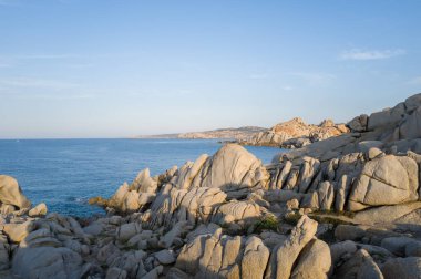 Sardunya 'nın Capo Testa kentindeki derin mavi Akdeniz' in üzerinde, öğleden sonra güneşinin altında berrak ve berrak bir gökyüzü altında, belirgin bir şekilde aşınmış granit kayalıklar yükselir..