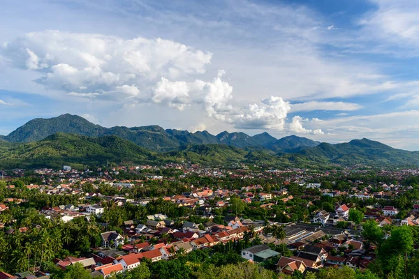 Kuzey Laos 'taki yemyeşil tepelerin arasına yerleşmiş Luang Prabang' ın geniş görüşü. Dramatik bulutlar ve canlı çatılar parlak mavi gökyüzünün altında canlı bir Güneydoğu Asya manzarası yaratıyor..