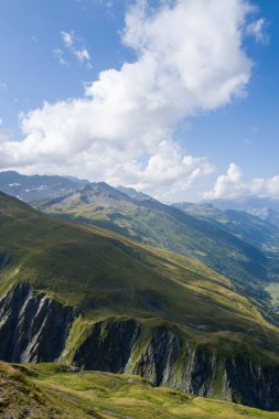 Güneşli yeşil yamaçlar ve engebeli Val Ferret tepeleri dalgalanan beyaz bulutlar ve yumuşak yaz ışıklarıyla dolu engin bir gökyüzünün altında uzanıyor..