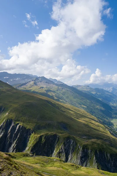 Güneşli yeşil yamaçlar ve engebeli Val Ferret tepeleri dalgalanan beyaz bulutlar ve yumuşak yaz ışıklarıyla dolu engin bir gökyüzünün altında uzanıyor..